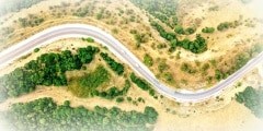 Aerial above view of a rural landscape with a curvy road running through it in Greece.