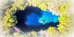 Melissani Cave Kefalonia viewed from above with tourists entering the cave by boat