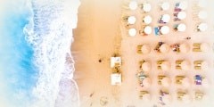 Sunbeds and umbrellas bird's eye view on sand beach in Greece