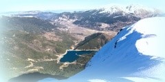 Panoramic view of Doxa lake and the snow covered Ziria mountain