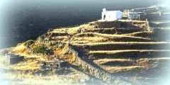 Church and stone huts in the old fields on Kythnos island.