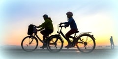 Silhouettes of people enjoying a walk by bicycle the seaside of the town during sunset