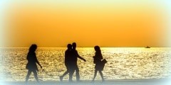 Silhouettes of people enjoying a walk by the seaside of the town during sunset