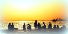 people relax on the waterfront at sunset