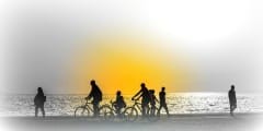 Silhouettes of people enjoying a walk by the seaside of the town during sunset