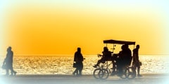 Silhouettes of people enjoying a walk by the seaside of the town during sunset