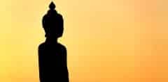 Silhouette of a Buddha sculpture with dark cloud at twilight tim