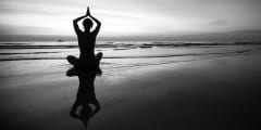 Woman doing meditation near the ocean beach. Black and white sil