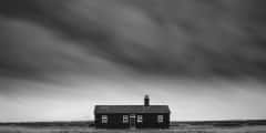 Remote desolate isolated house under dark stormy sky during Winter landscape conceptual image