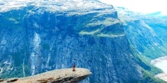 Man standing iconic cliff at Trolltunga Norway