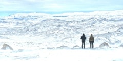 Two girls standing on the top of the hill and together watching