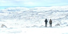 Two girls standing on the top of the hill and together watching