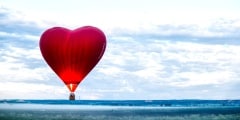 Red air balloon heart rises up at dawn